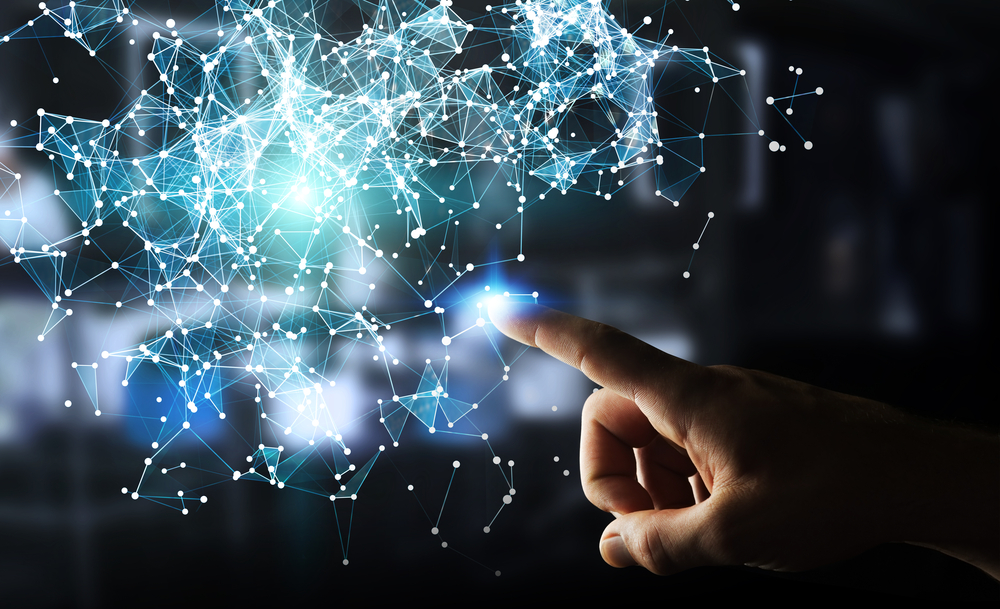 Hand pointing to 3D rendering of blue network nodes on dark, blurred background