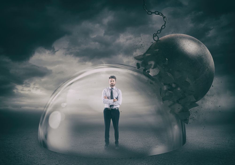 Businessman standing inside a domed shield amid a dark storm