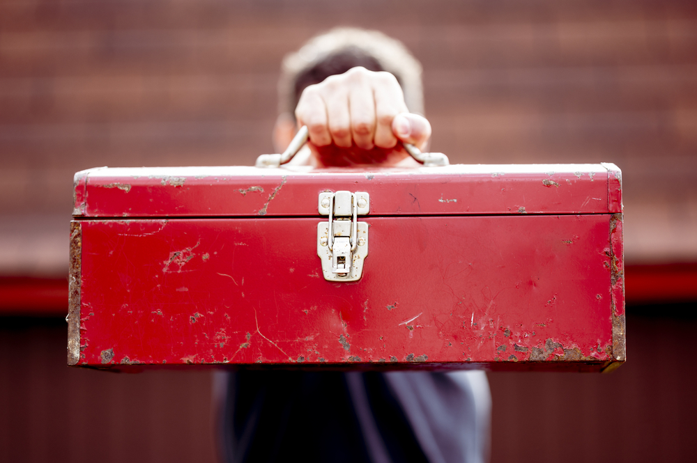Closeup shot of a red square toolbox held in front of a man